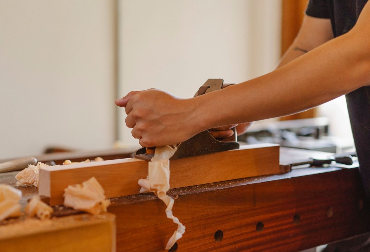 Personnage utilisant un planeur sur bois, éclats de bois dispersés sur une table de travail