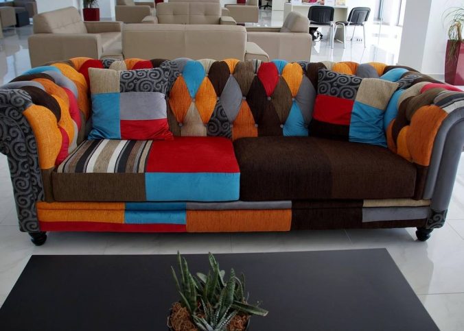 Canapé coloré aux motifs patchwork, table basse noire, plante, intérieur moderne