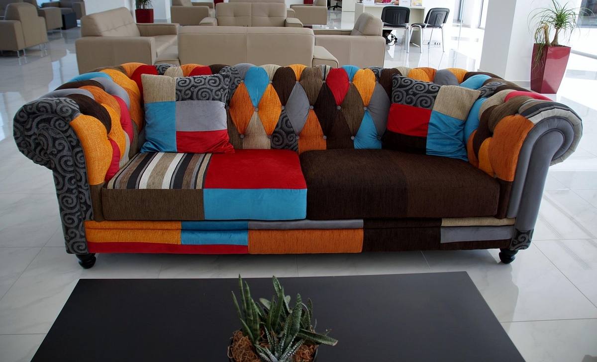 Canapé coloré aux motifs patchwork, table basse noire, plante, intérieur moderne