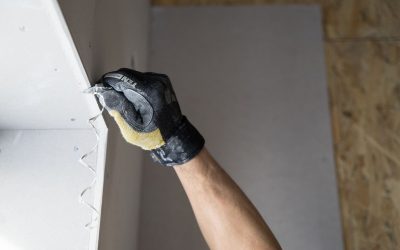 Main gantée applique de la pâte à joint sur plaque de plâtre