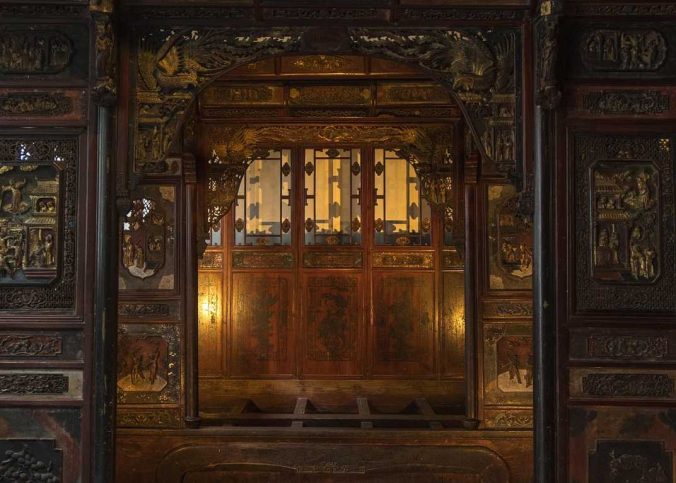 Porte en bois sculptée, panneaux décorés, lumière chaleureuse, intérieur traditionnel